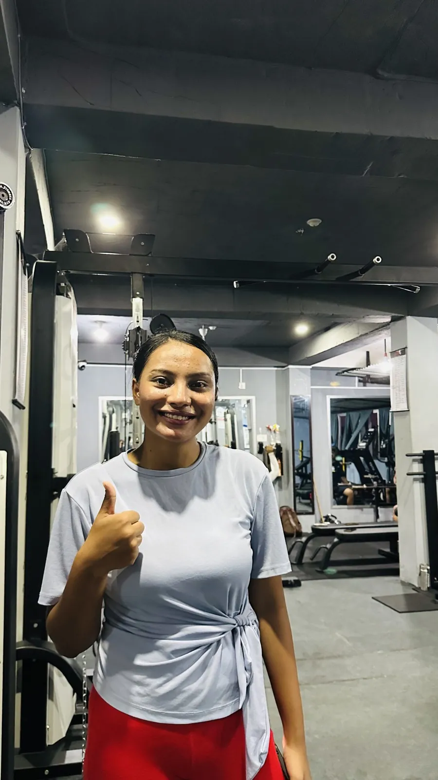Smiling woman member giving a thumbs up on the training floor at Apex Fitness Centre